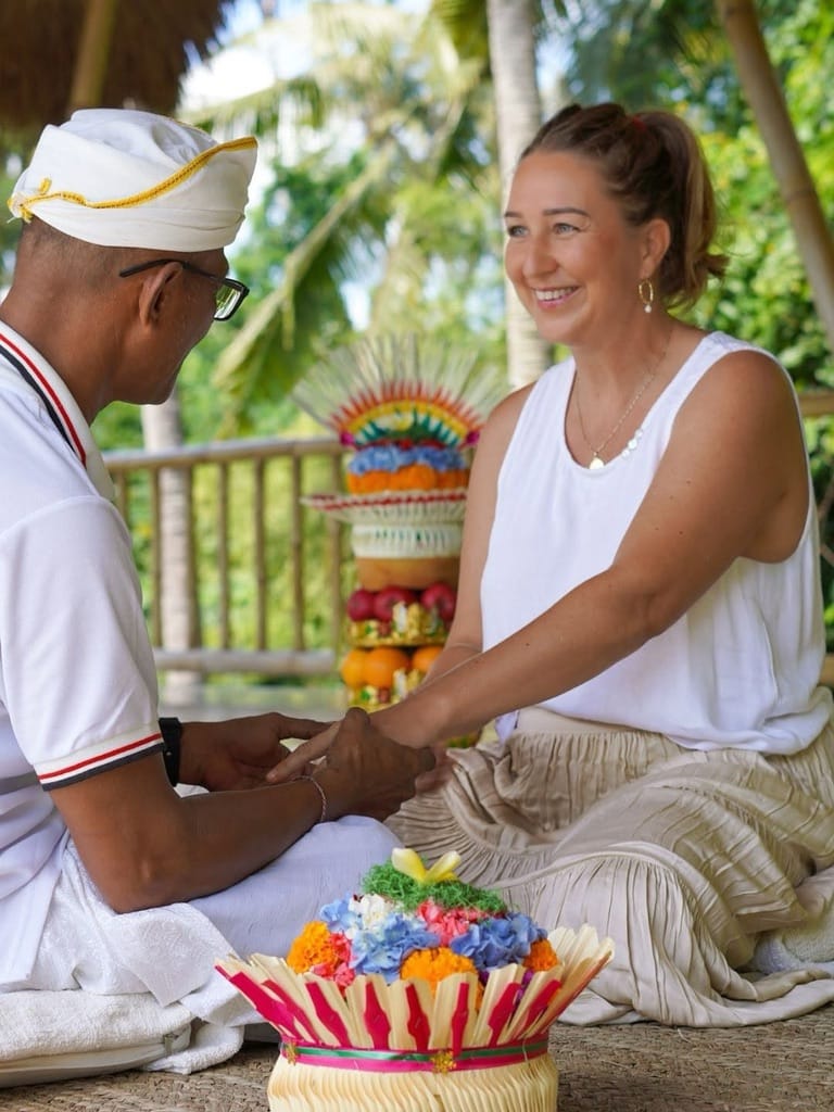 Guest recieiving tri desna healing ceremony braclet at Goddess Retreats Ubud reflecting on Tri Desna philosophy with balinese healer