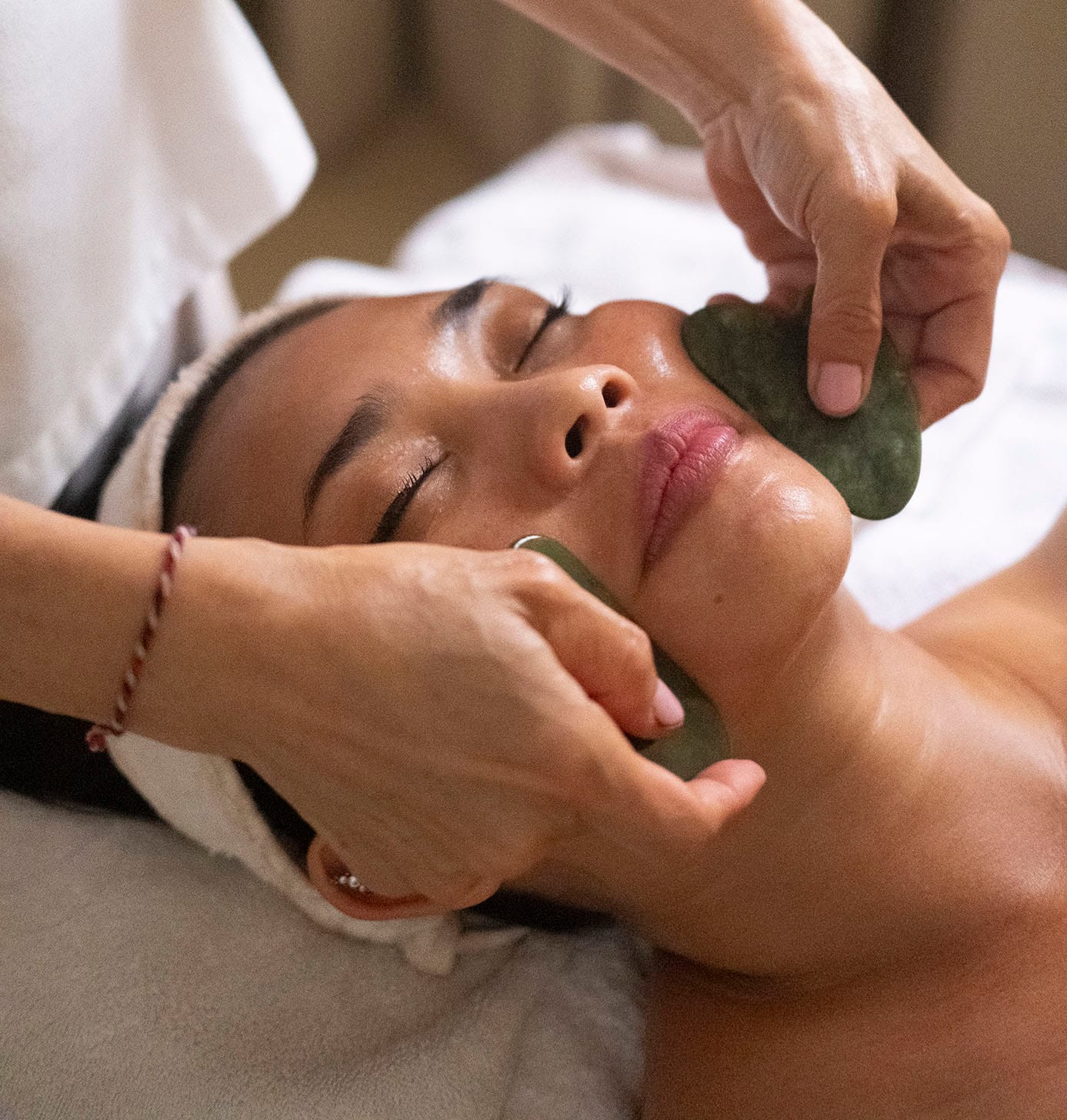 Woman enjoying a Gua Sha facial during a spa and self-care day at a serene Bali retreat.