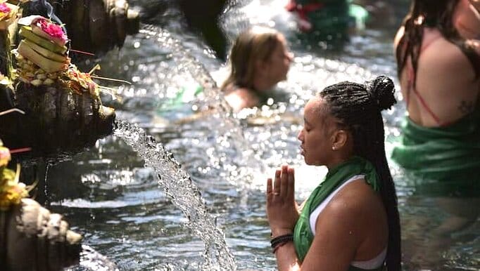 Sacred temple blessing at the Holy Spring Temple, Tirta Empul, Bali, during a spiritual retreat, with participants immersing in the purifying waters.