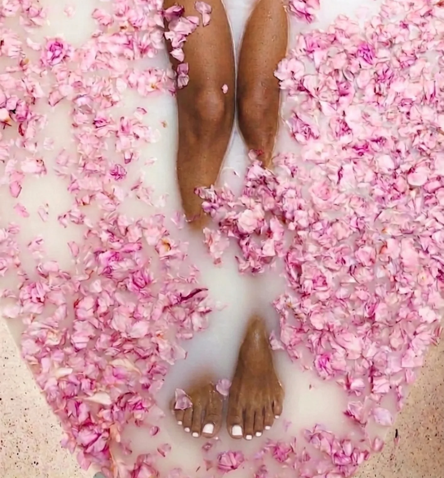 Woman relaxing in a flower bath filled with pink petals at a holistic wellness retreat in Bali.