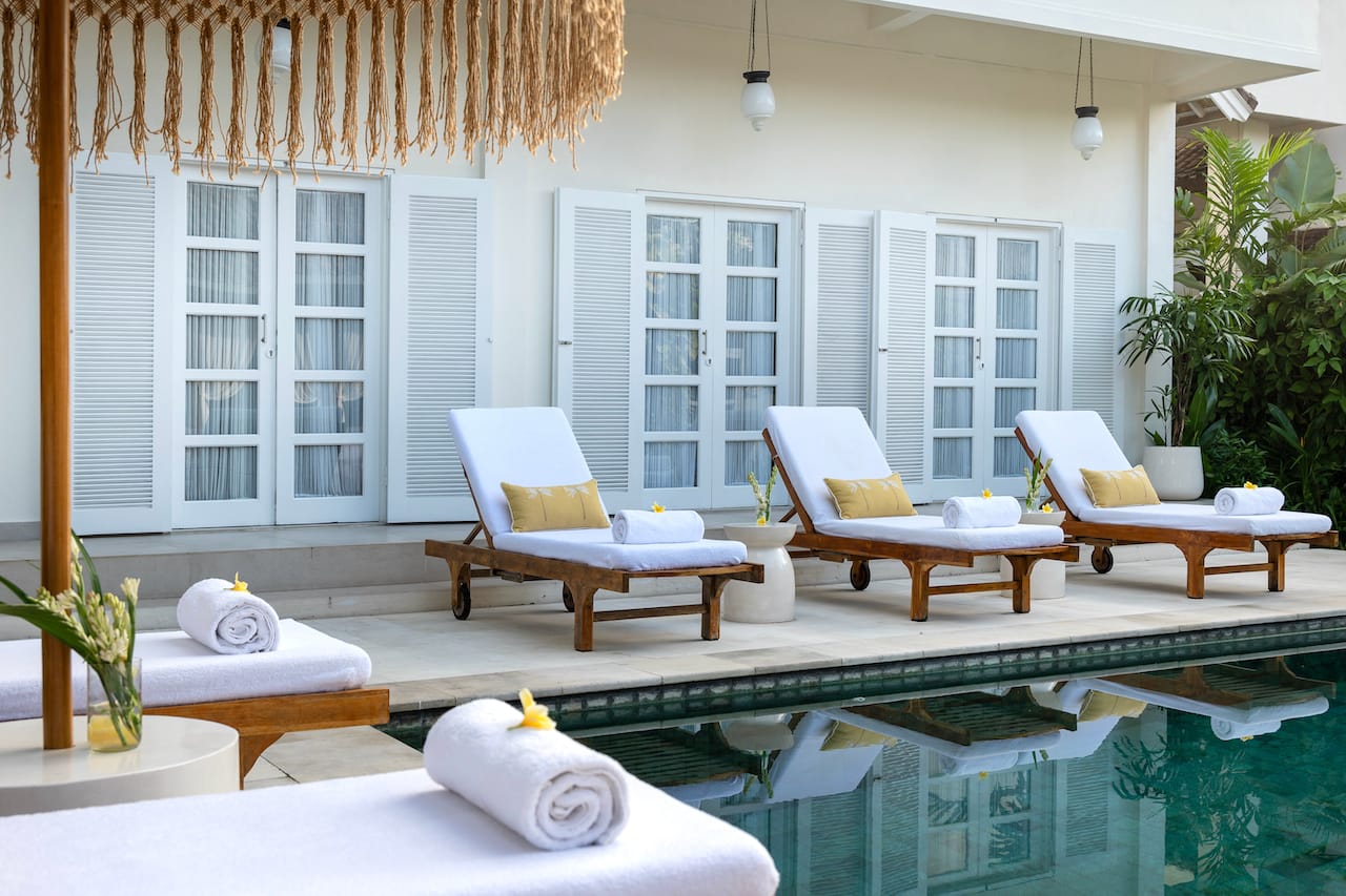 Serene poolside view at a luxury Bali retreat, surrounded by lush tropical greenery and tranquil ambiance for relaxation and rejuvenation.