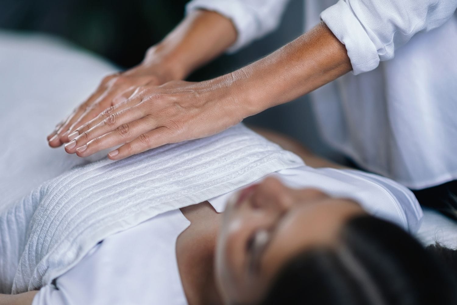 Reiki energy healing session with hands placed gently on a person's body to promote relaxation and balance