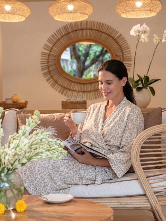 Solo Woman in a robe enjoying tea and reading a magazine at a Bali wellness and spa retreat.