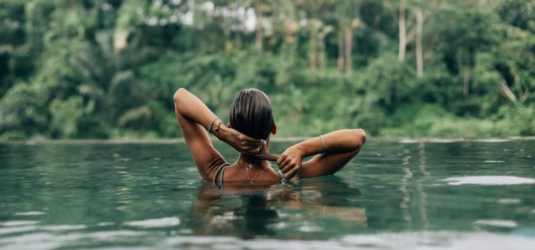 woman in pool looking at bali jungle on a wellness retreat in ubud