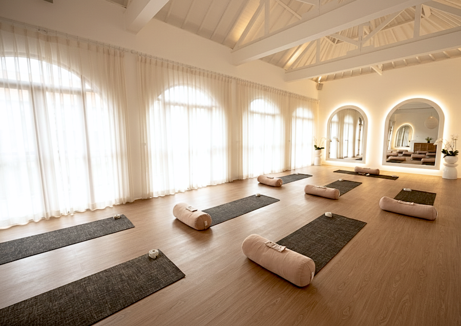 Serene white walled yogd room with linen curtains and yoga mats and bolsters laid out for a yoga class at a womens yoga retreat in Canggu Bali
