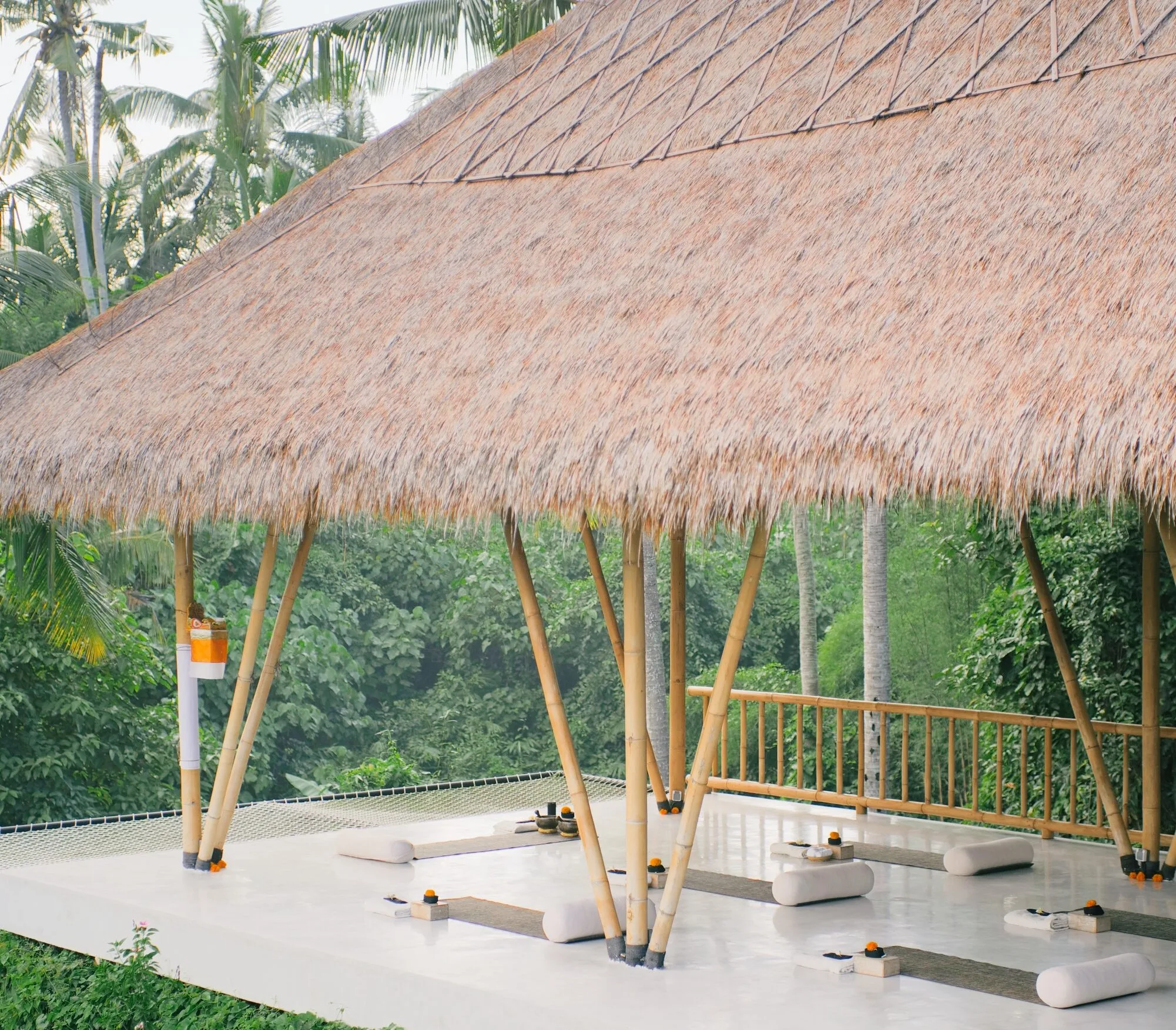 Open-air yoga pavilion surrounded by lush tropical greenery at a holistic wellness retreat in Bali.