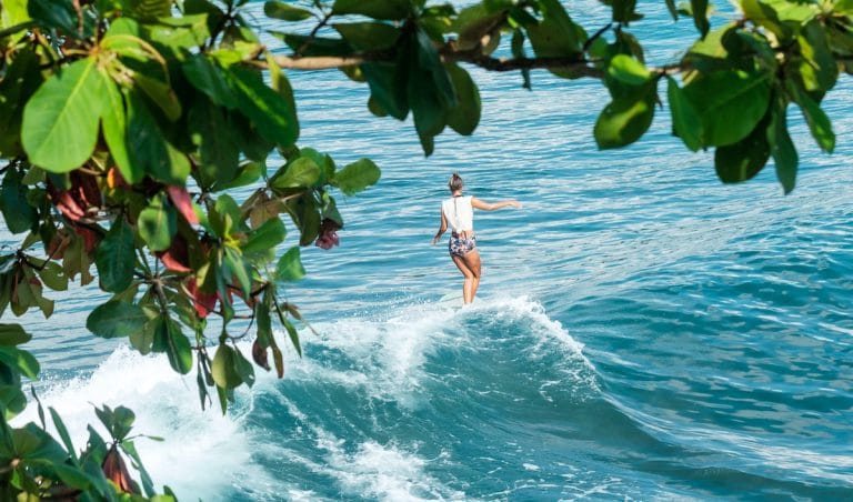 A surfer girl in bali, Indonesia, riding a wave on her longboard.