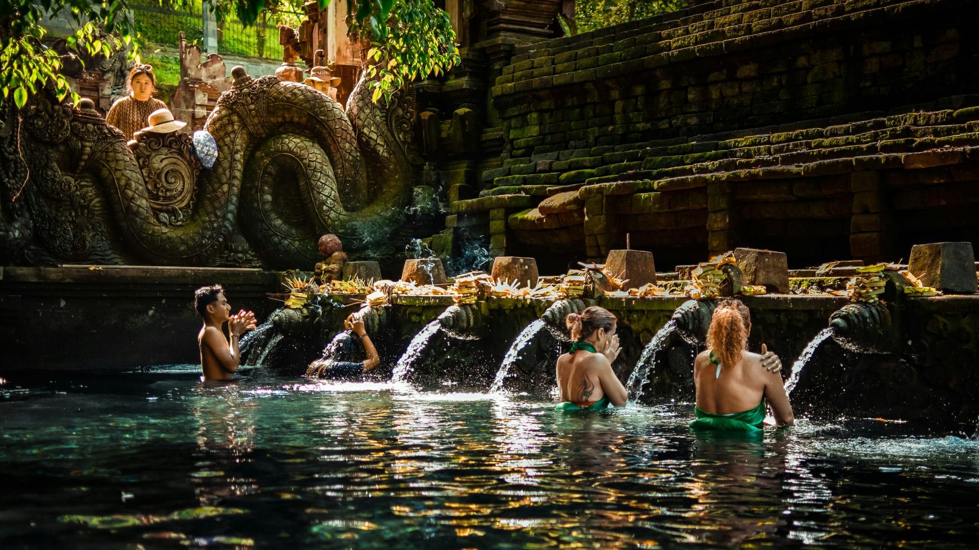 Guests geting holy spring blessing at tirta empul melukat at Goddess Retreats Ubud during sunrise after Bali healing ceremony